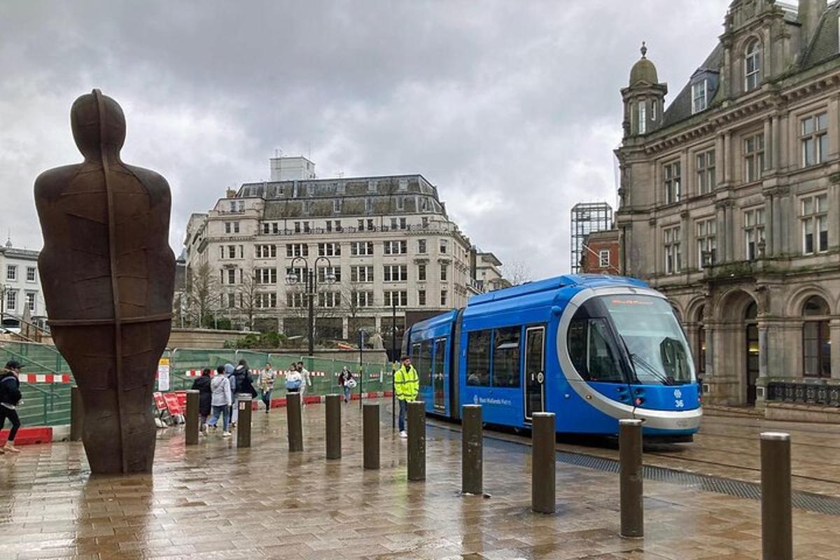 a blue train traveling through a city with a statue