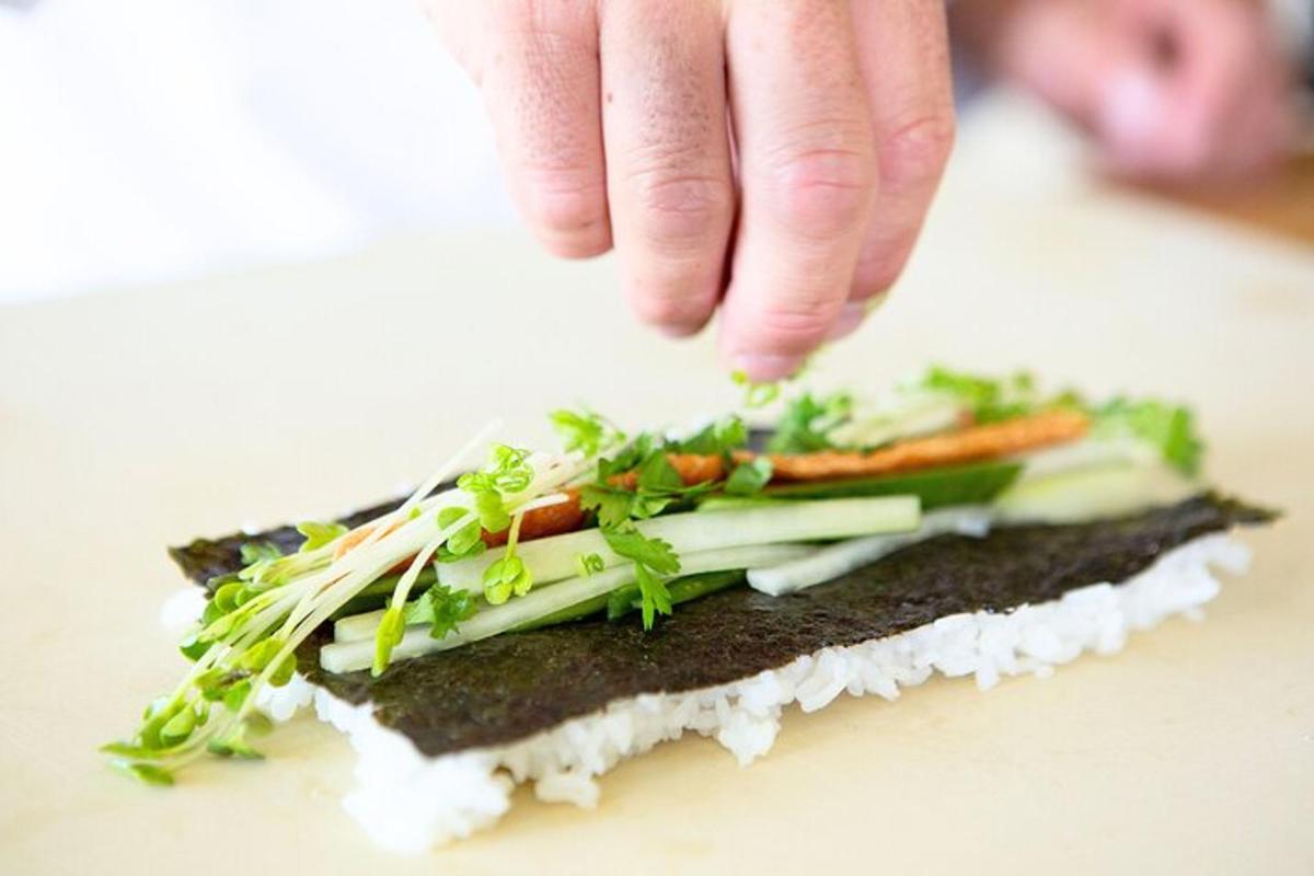 a person sprinkling vegetables on top of a sandwich