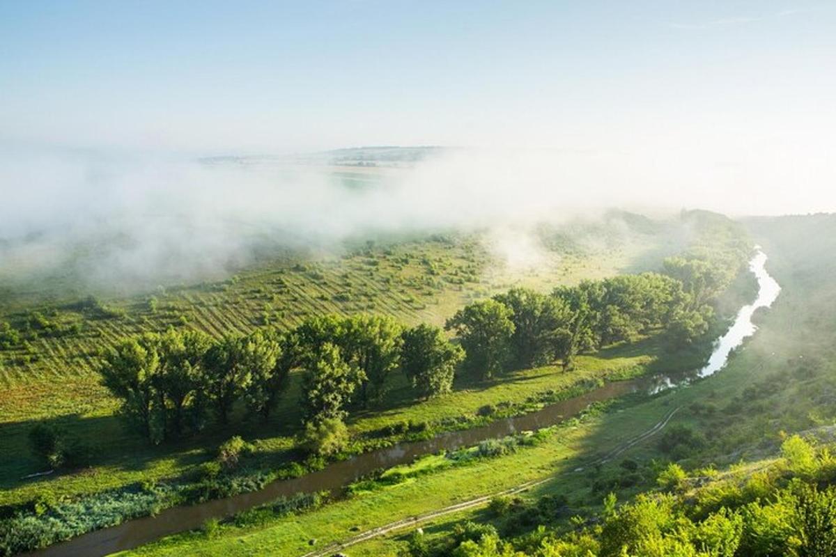 Una vista aérea de un campo brumoso con un río.
