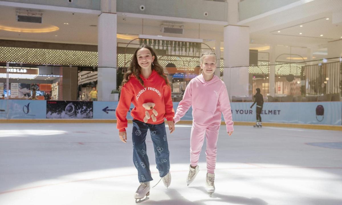 a girl and a boy skating on an ice rink