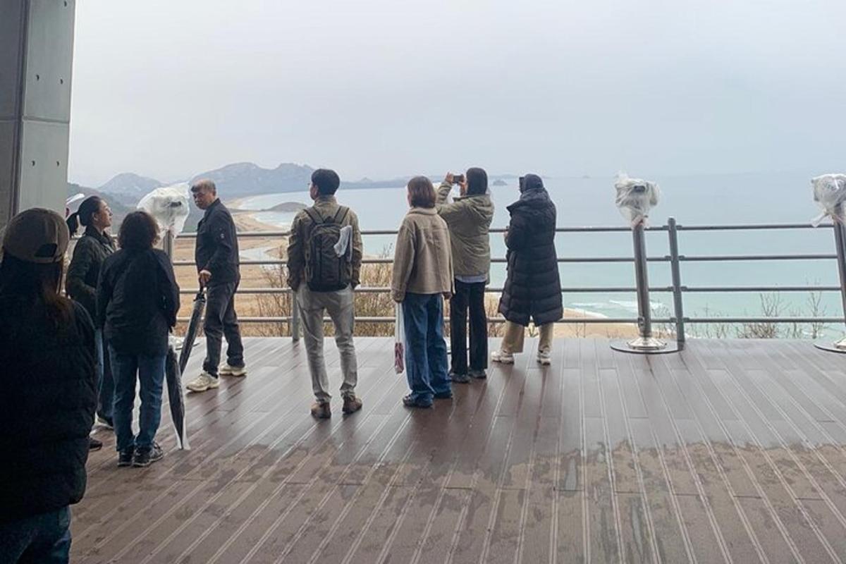 Un grupo de personas de pie en una plataforma de observación mirando el océano.