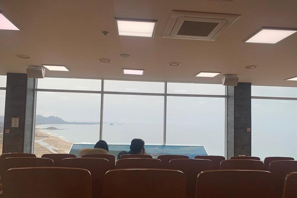 Dos personas sentadas en un auditorio mirando el océano.