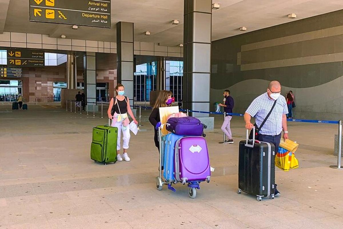 μια ομάδα ανθρώπων που περπατούν σε ένα αεροδρόμιο με τις αποσκευές τους
