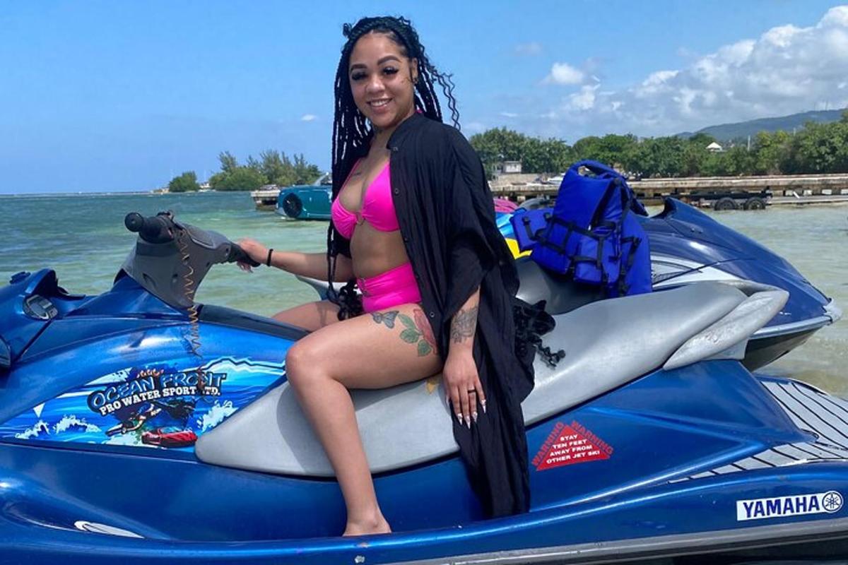 egy rózsaszín bikiniben lévő nő ül egy jetski-n