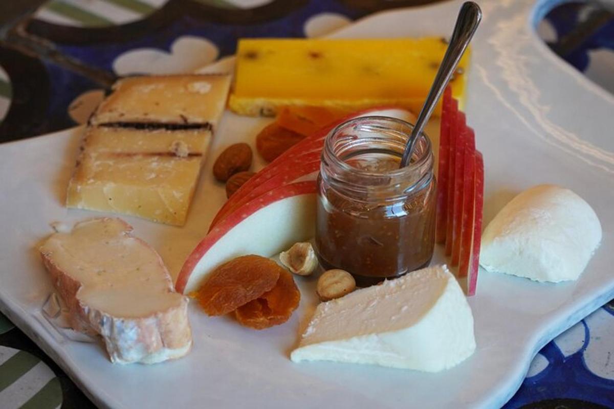 Un plato de diferentes tipos de queso y un tarro de salsa.