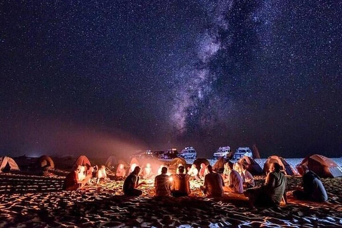 Un grupo de personas sentadas alrededor de una fogata por la noche.
