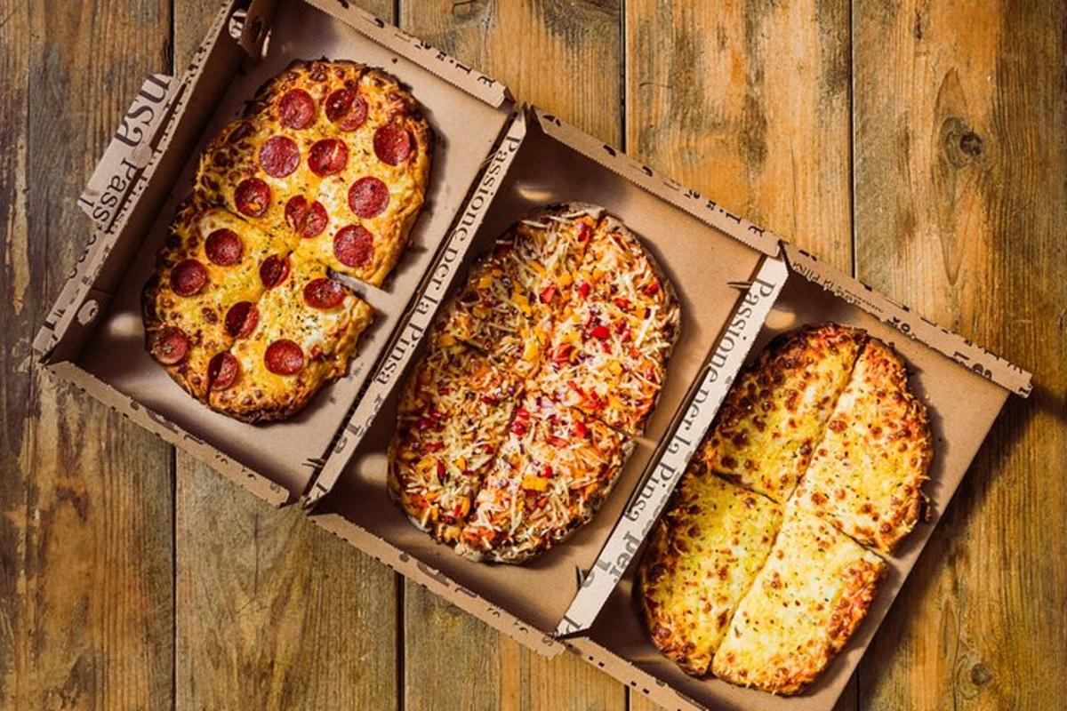 tre pizzaer i esker på et trebord