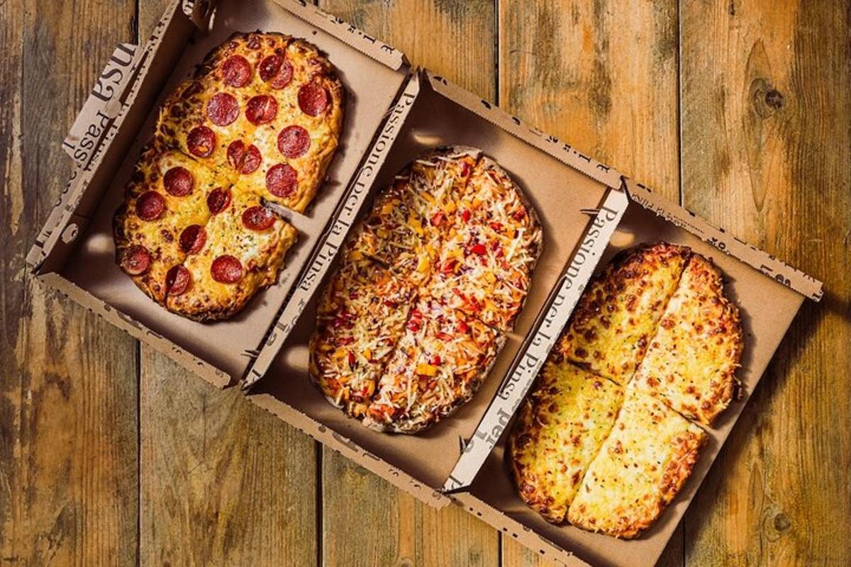 trzy pizze w pudełku na drewnianym stole