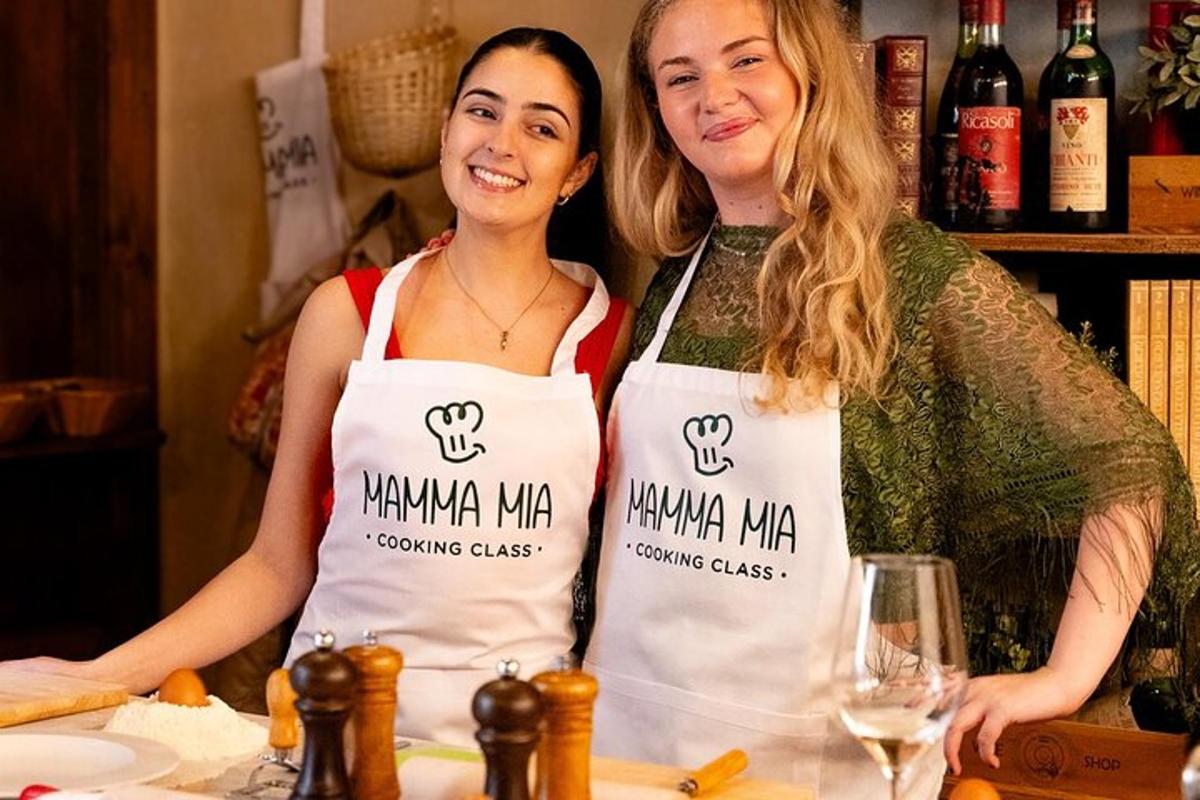 duas mulheres em pé em uma cozinha usando aventais