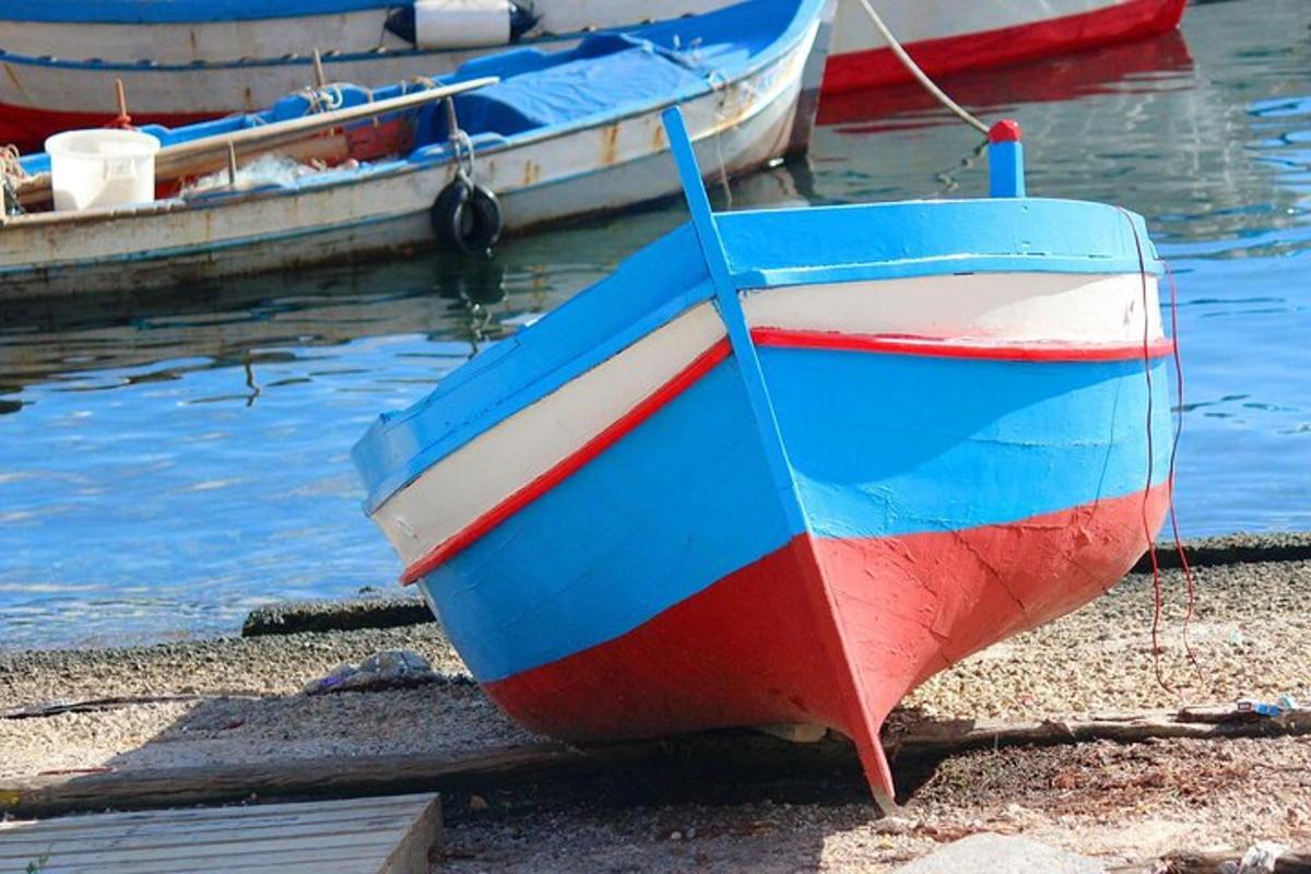 Un barco rojo, blanco y azul sentado en la orilla