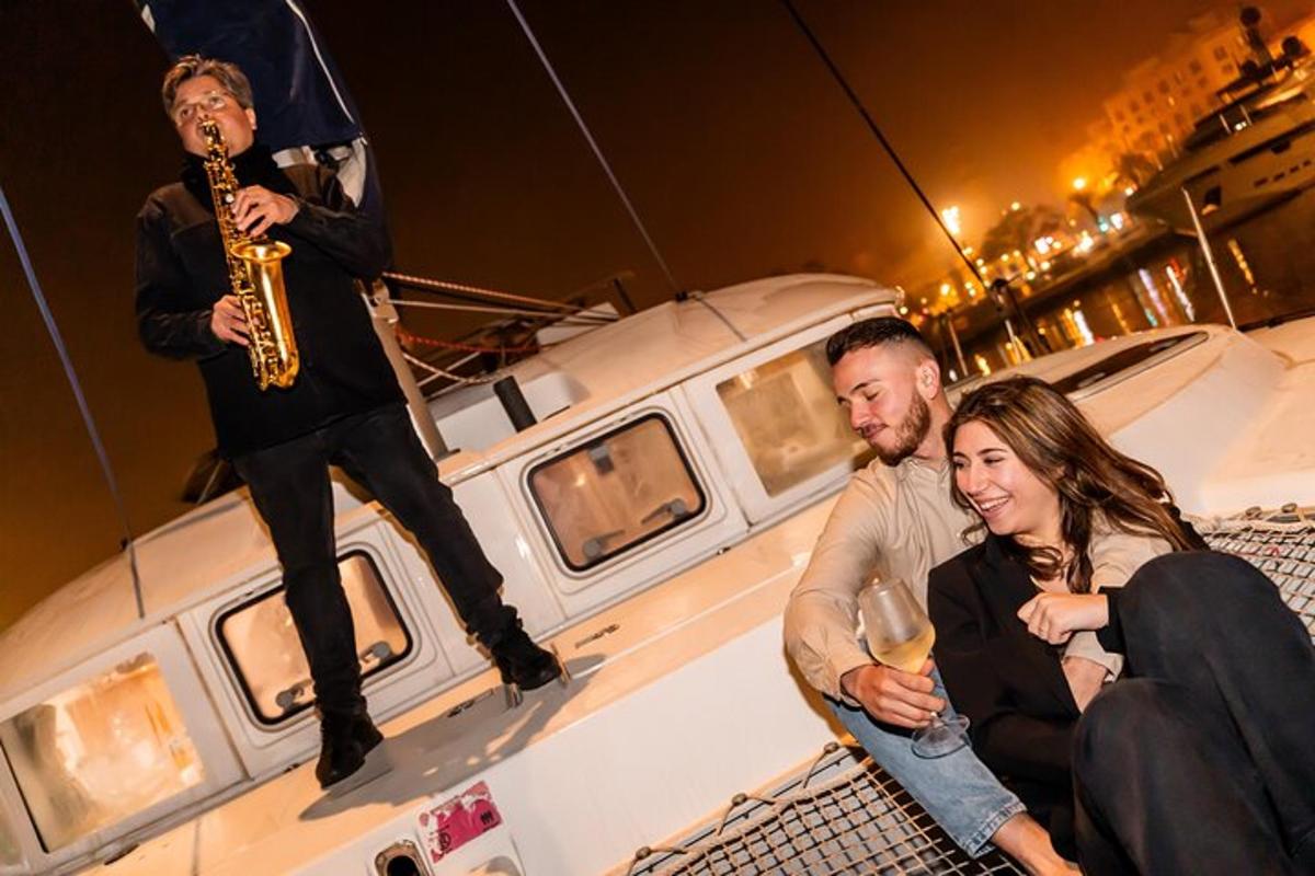muž hrající na saxofon a dva lidé sedící na lodi