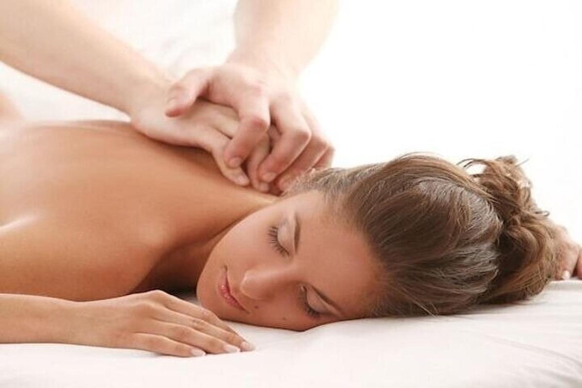 a woman laying on a bed receiving a back massage