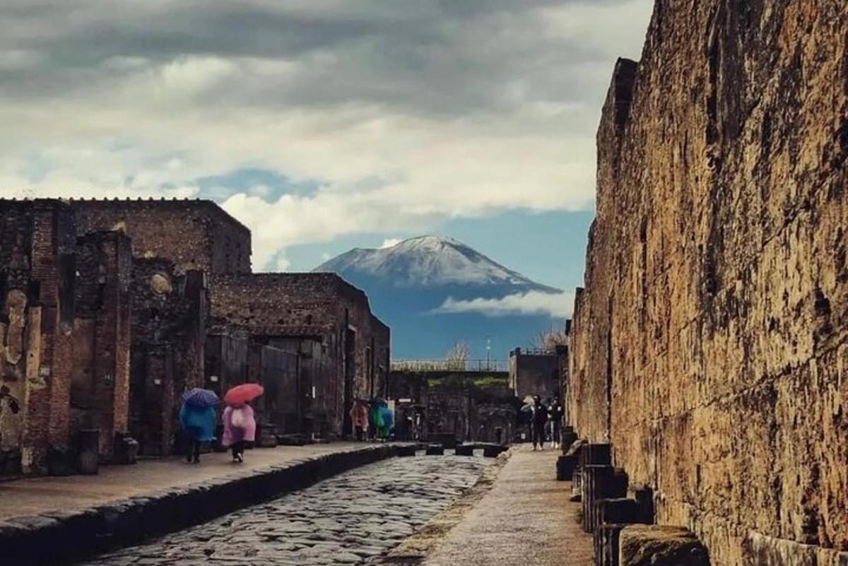 pessoas caminhando por uma rua com uma montanha ao fundo