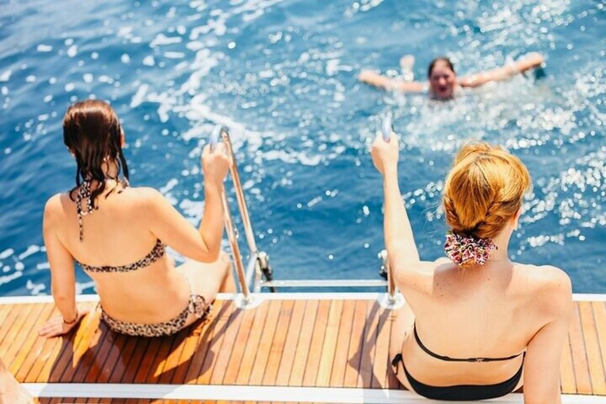 two women sitting on a boat watching a man in the water