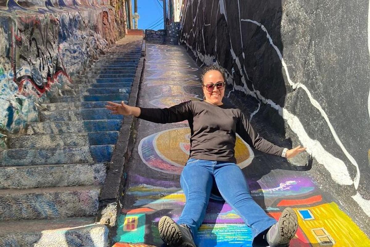 Una mujer sentada en el suelo en unas escaleras con grafitis.
