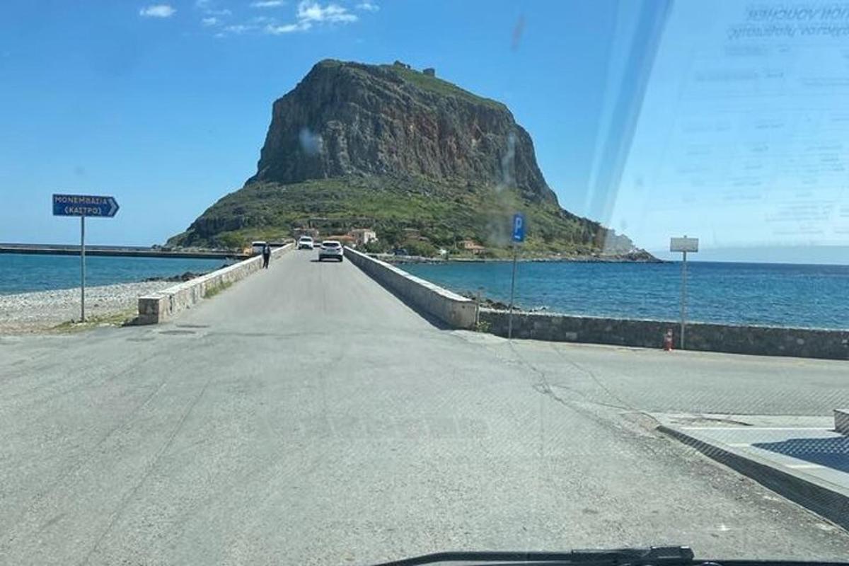 a road with a mountain in the middle of the ocean