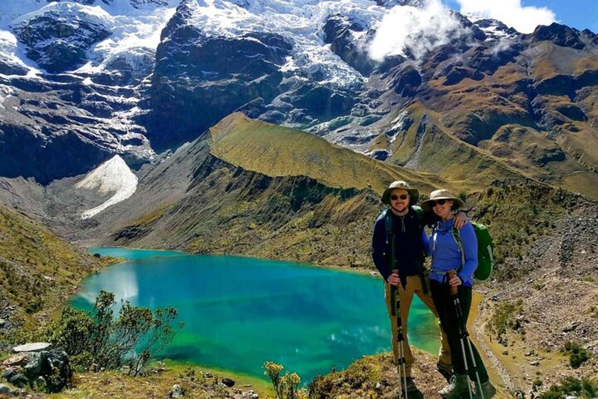 due persone in piedi sulla cima di una montagna con un lago