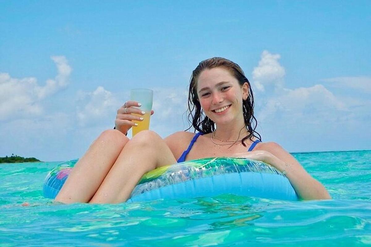 een meisje zittend op een vlot in het water met een drankje