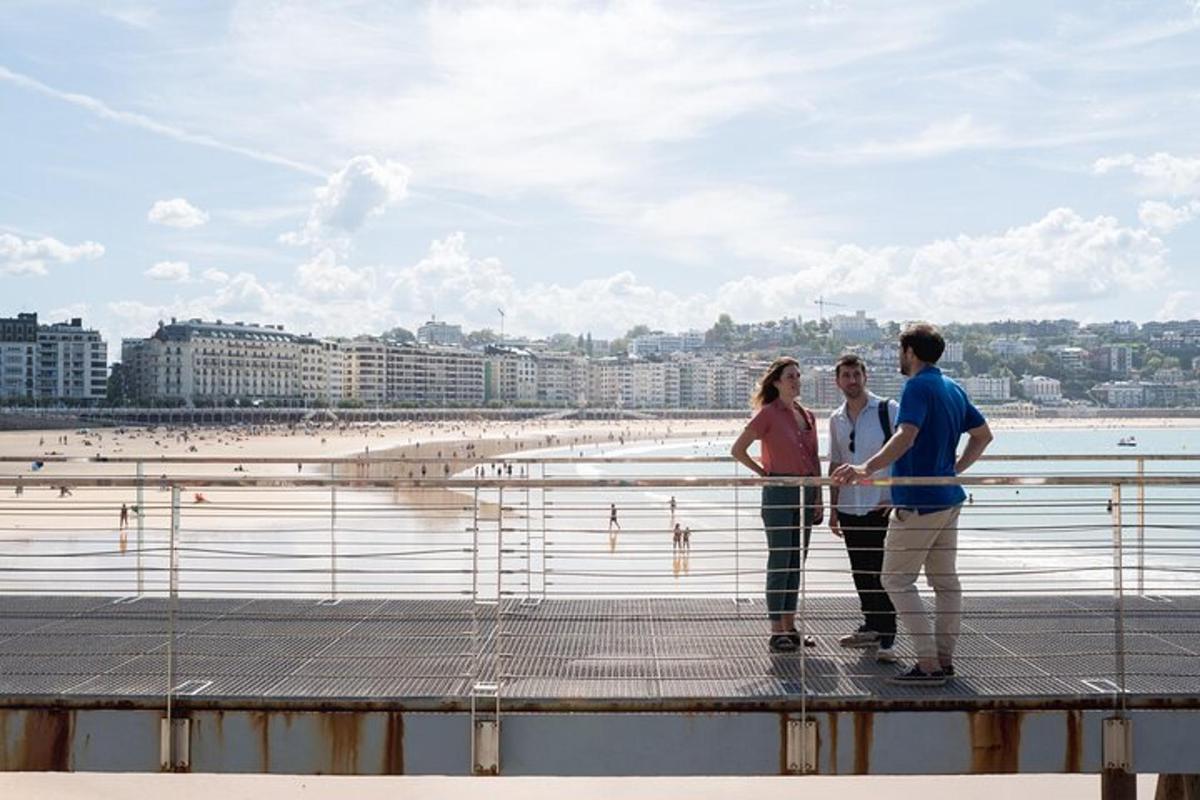 three people standing on a pier near the beach