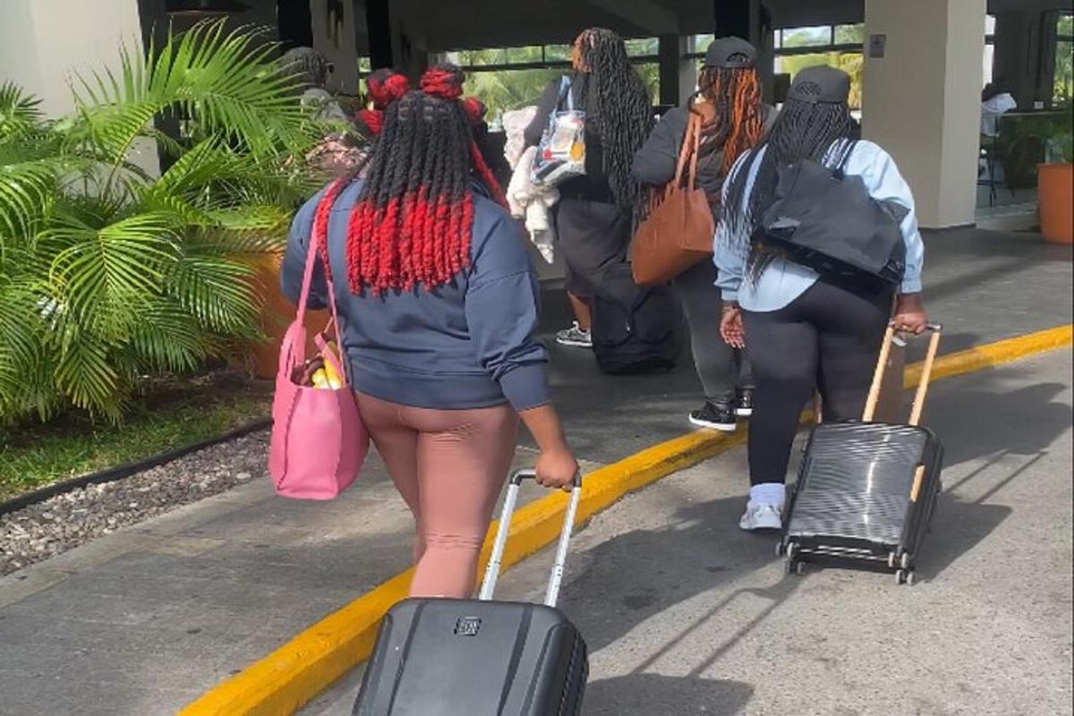 un gruppo di persone che camminano lungo un marciapiede con i bagagli