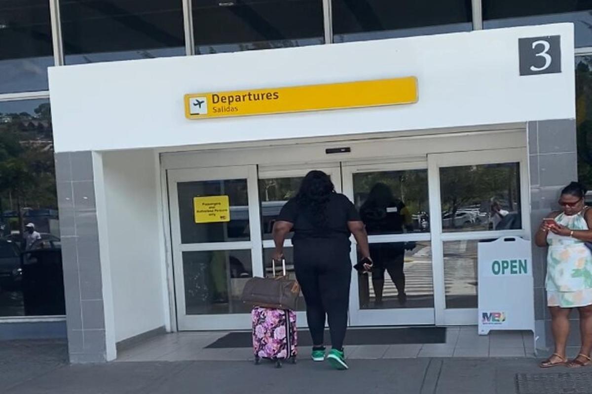 una donna che esce da un aeroporto con i suoi bagagli