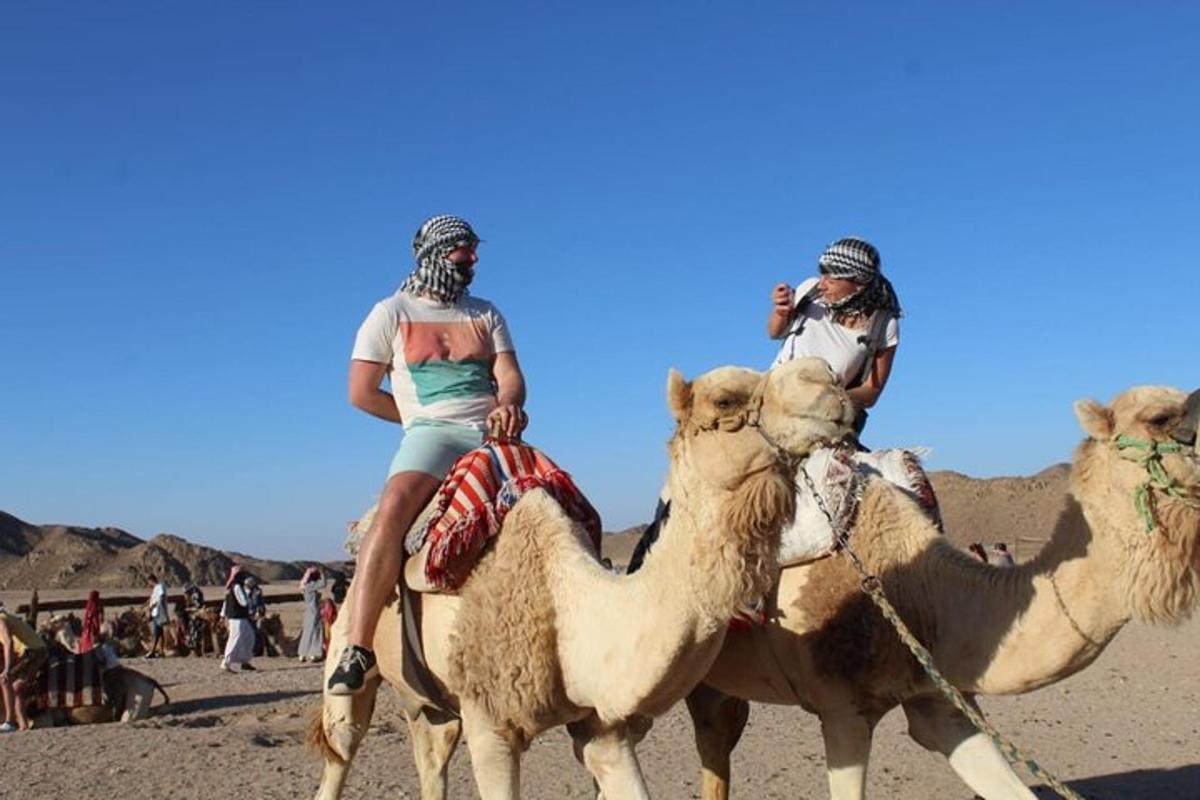 due persone a cavallo di un cammello nel deserto