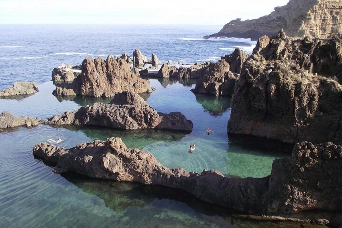 skupina ljudi, ki plavajo v skalnem bazenu v oceanu