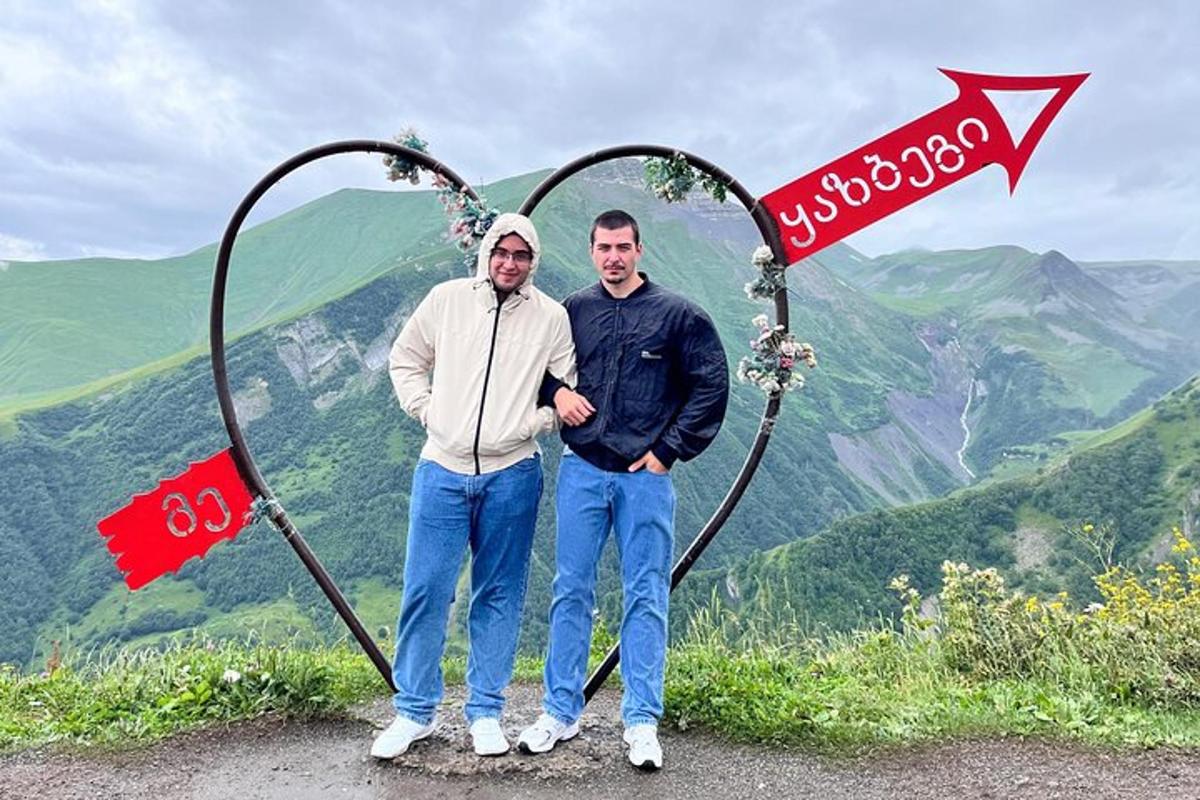dos homes drets davant d'un rètol en una muntanya