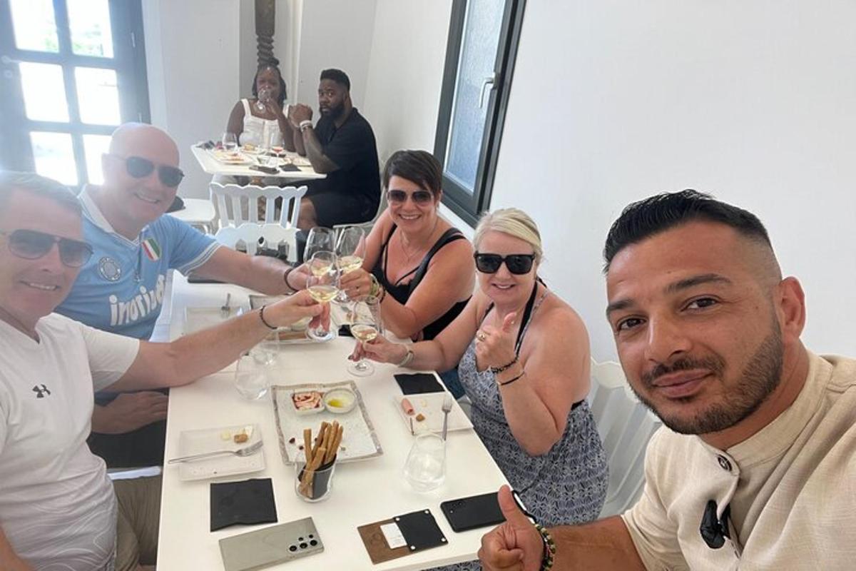 un gruppo di persone sedute attorno a un tavolo con bicchieri di vino