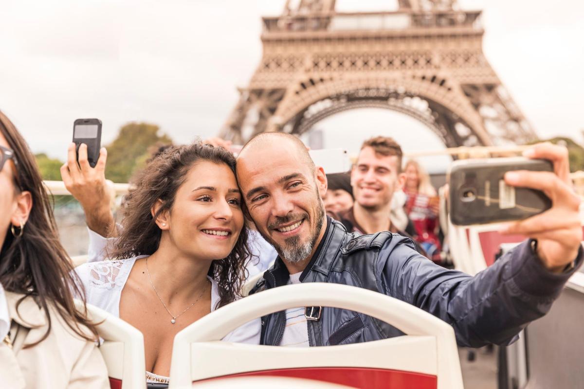 a man taking a picture in front of the eiffel tower