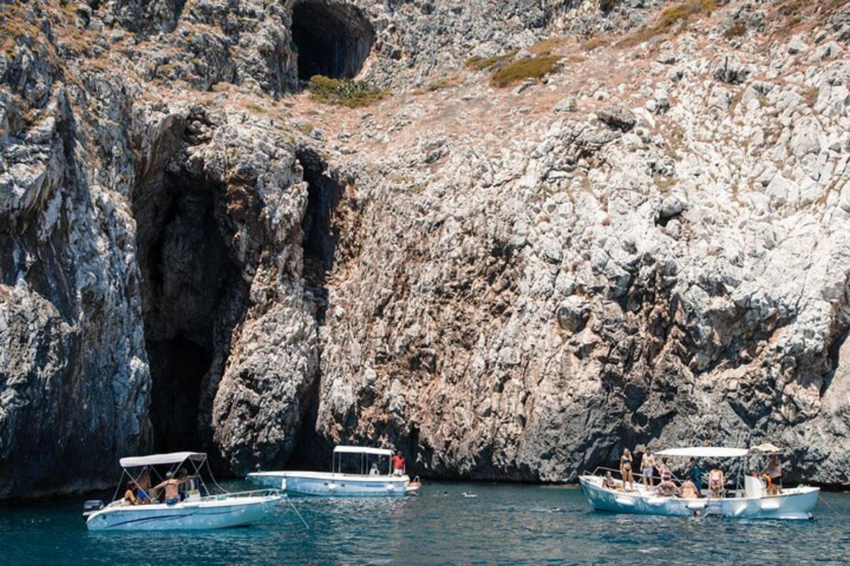 Dos barcos en el agua junto a un acantilado rocoso