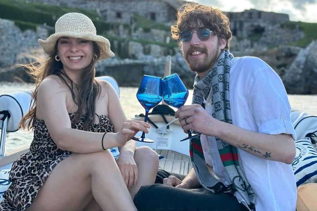 um homem e uma mulher sentados em um barco com taças de vinho