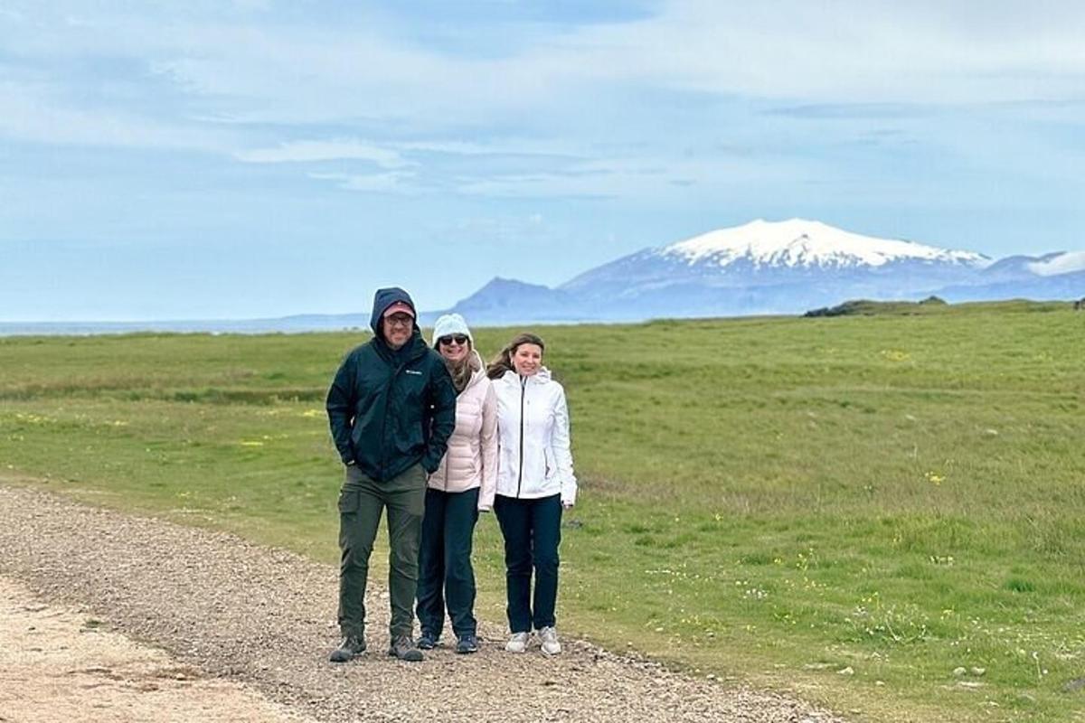 um grupo de pessoas em pé em uma estrada de terra com uma montanha