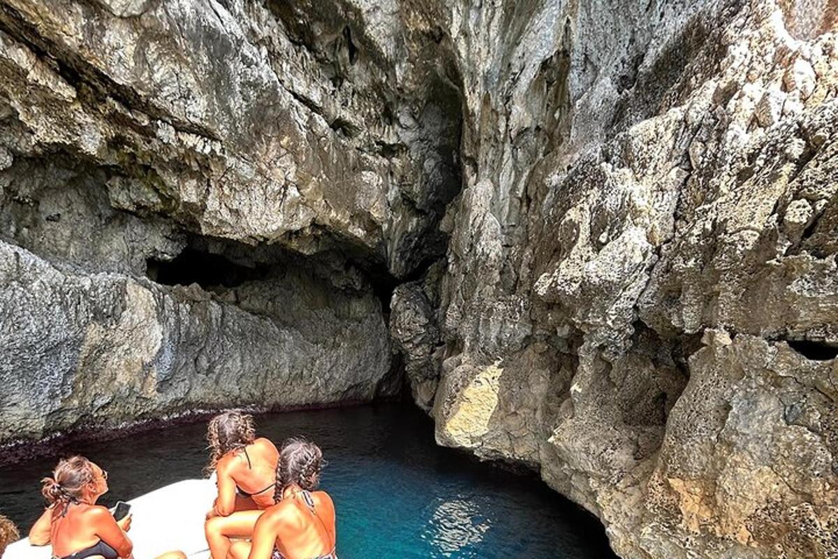 tre donne in costume da bagno sedute su una barca in una grotta