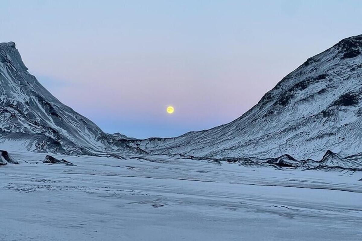 una luna che sorge tra due montagne innevate