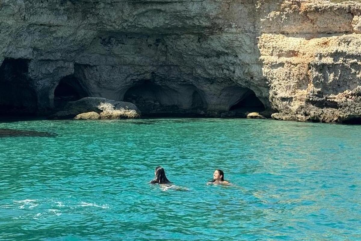 dua orang berenang di air dekat gua