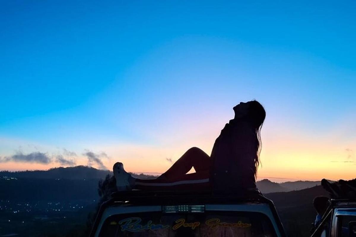 uma pessoa sentada na parte de trás de um veículo observando o pôr do sol