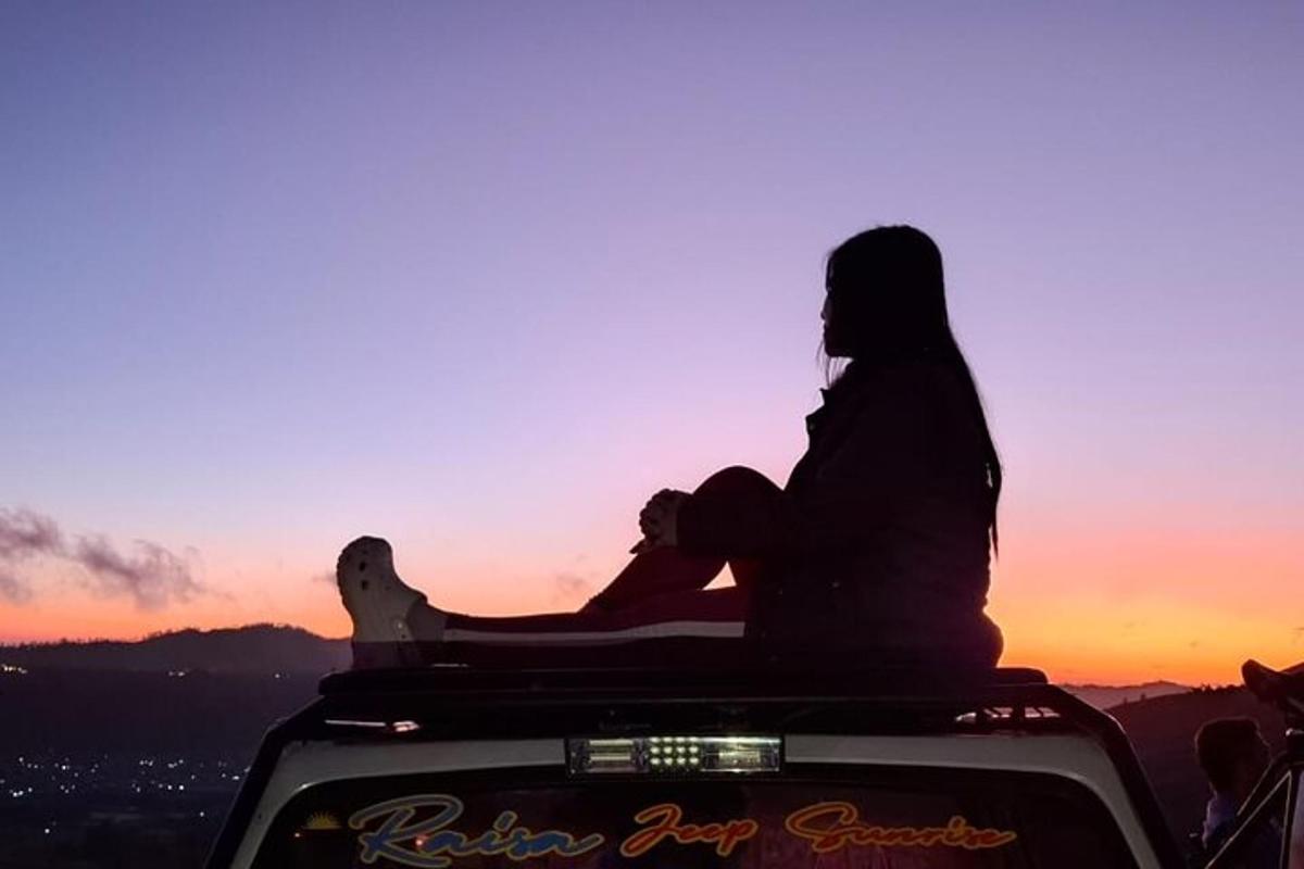 uma mulher sentada na parte de trás de um veículo ao pôr do sol