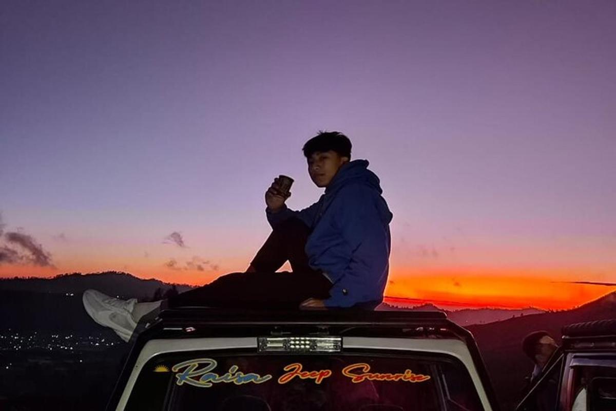 um homem sentado na parte de trás de um carro ao pôr do sol