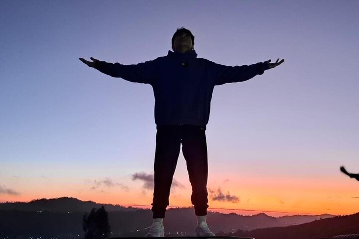 um homem em pé em uma prancha de snowboard com os braços estendidos