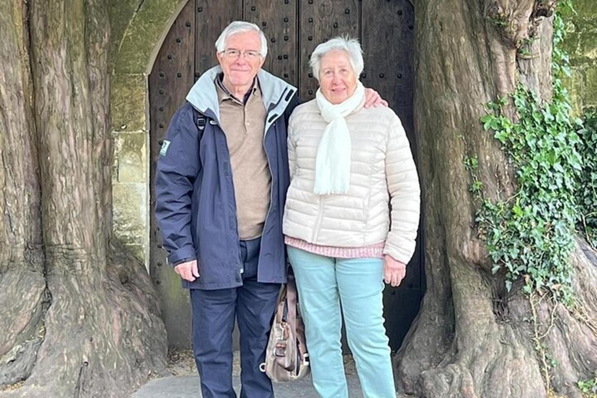 Un hombre y una mujer mayores de pie frente a un árbol.