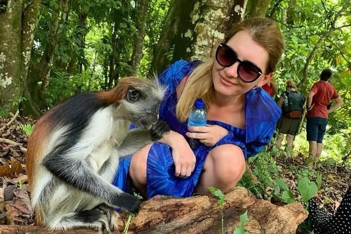 žena v šatách držiaca opicu s fľašou s vodou