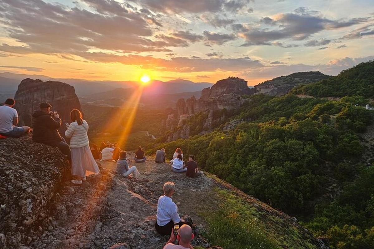 a group of people sitting on a mountain watching the sunset
