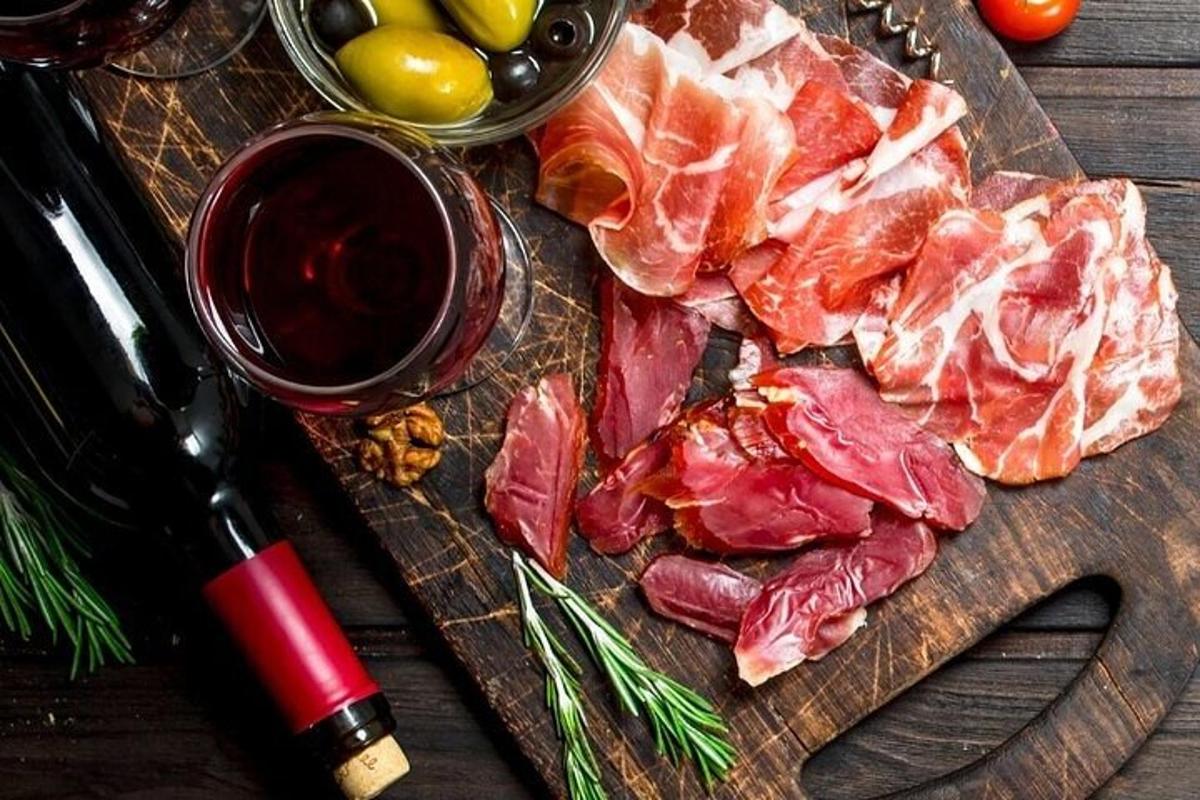 uma tábua de corte de madeira com carne e uma taça de vinho