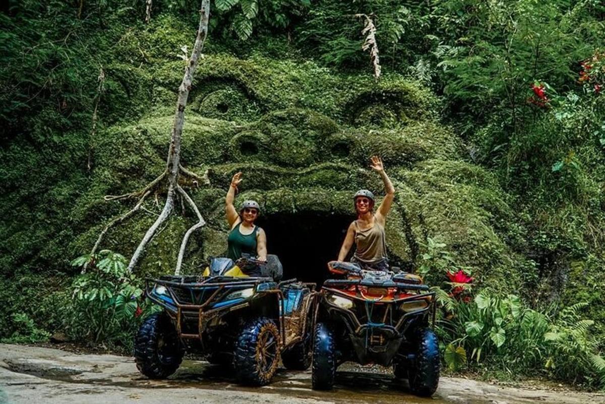 dua orang duduk di atv dengan tangan mereka ke udara