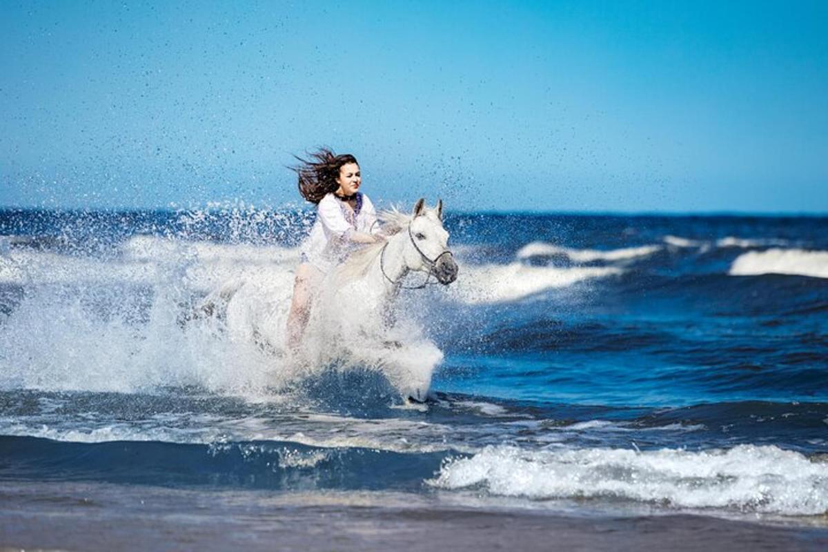 žena jedoucí na bílém koni v oceánu