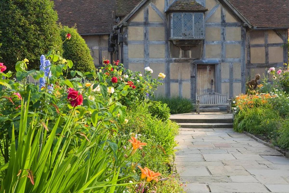 a garden with flowers and a building with a bench