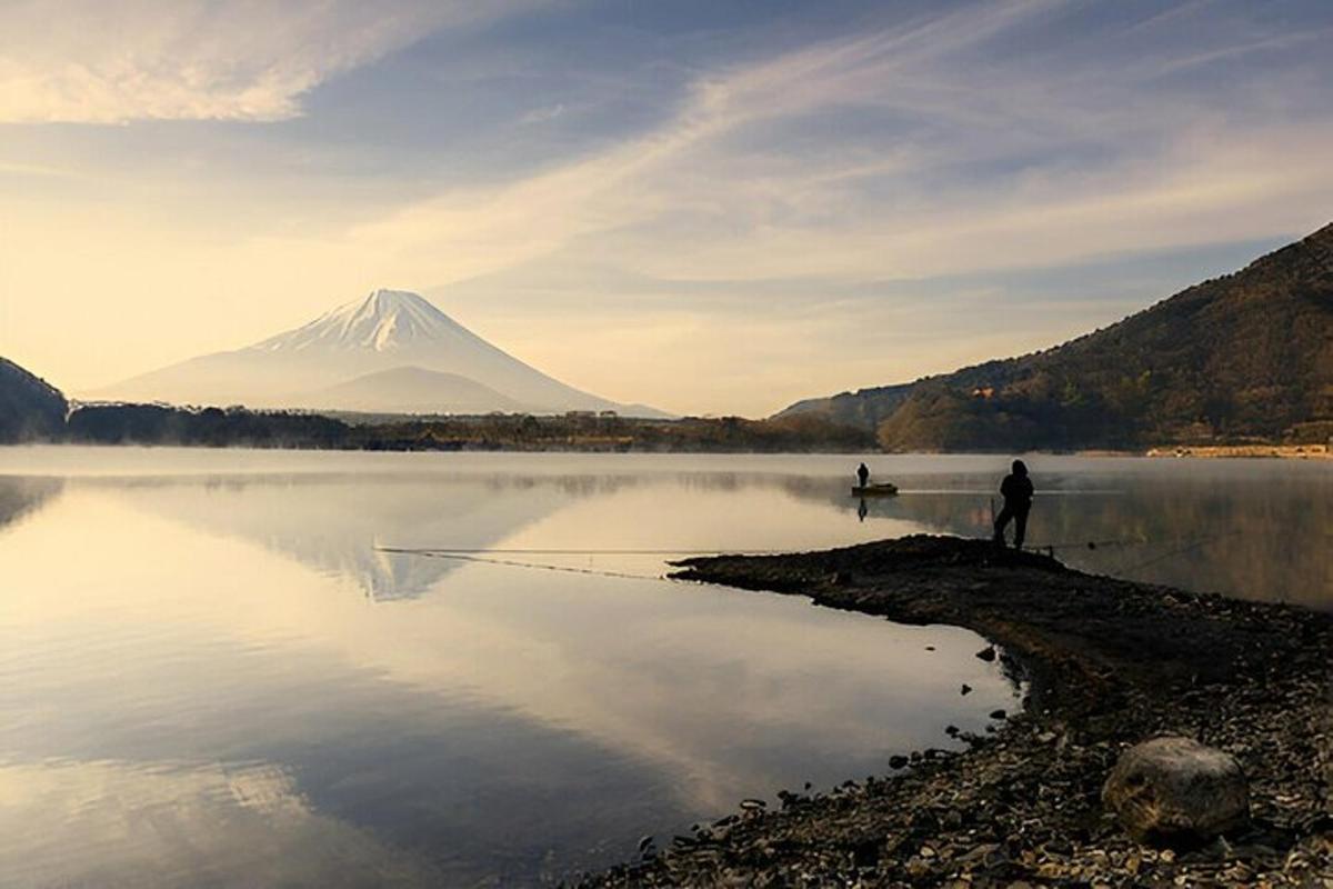 due persone in piedi sulla riva di un lago con una montagna