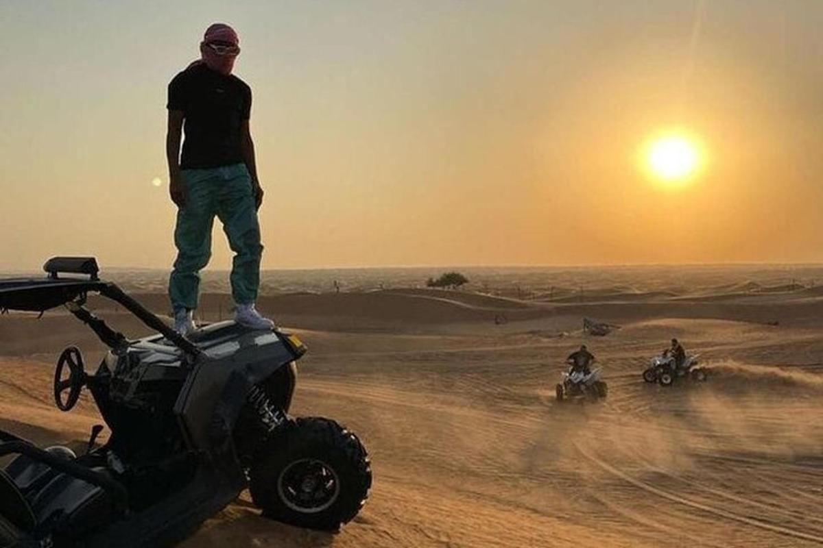 un home dret sobre un quad al desert