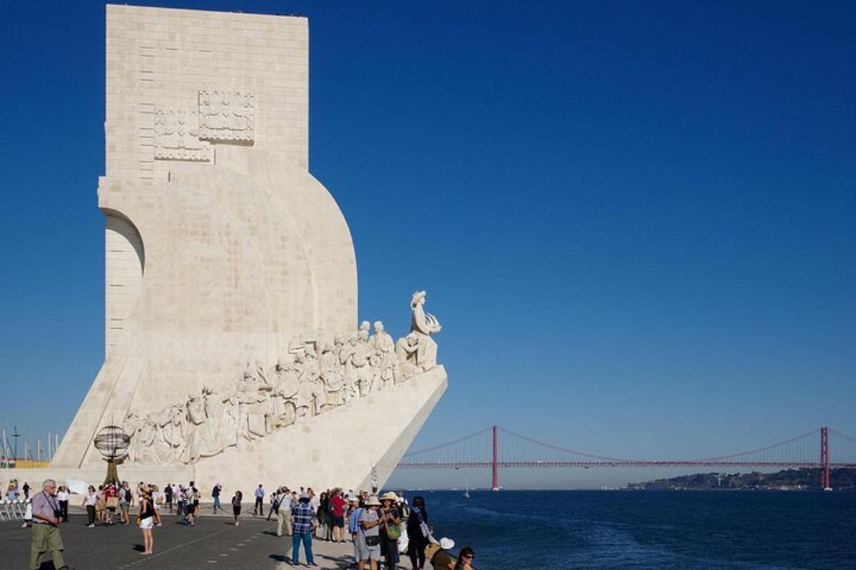 una folla di persone in piedi attorno a un monumento con un ponte sullo sfondo